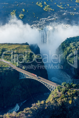 Aerial view of Victoria Falls behind bridge