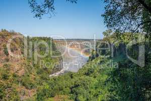 Rainbow spanning gorge beneath Victoria Falls Bridge
