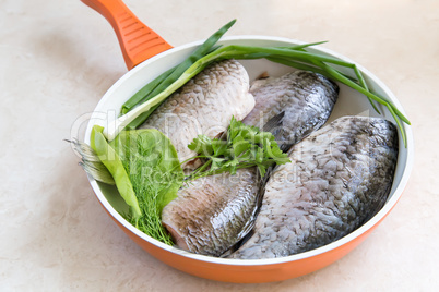 Fish and components for her preparation in a large skillet.