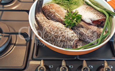 Fish and components for her preparation in a large skillet.