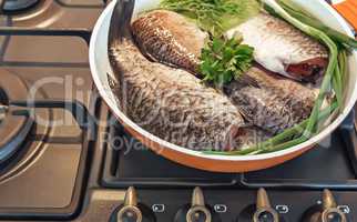 Fish and components for her preparation in a large skillet.