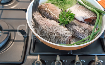 Fish and components for her preparation in a large skillet.