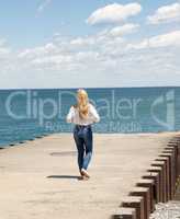 Young blond woman walking on a pier.