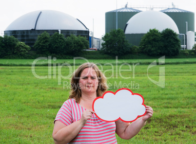 Frau hält ein Schild vor Biogasanlage
