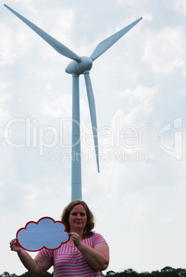 Woman holding a sign in front of a wind turbine