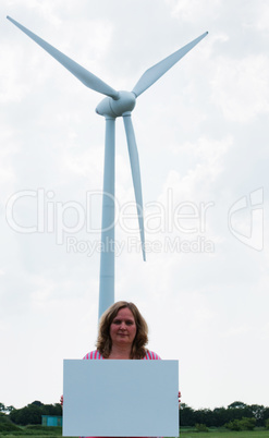 Woman holding a sign in front of a wind turbine