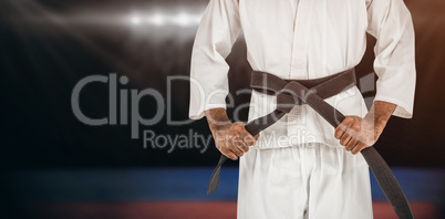 Composite image of fighter tightening karate belt