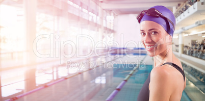 Fit swimmer standing by the pool smiling at camera