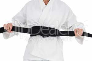 Female athlete tightening her judo belt