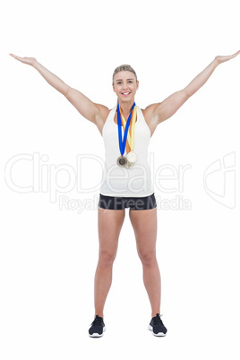Female athlete raising her arms and wearing medals
