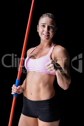 Female athlete holding a javelin and showing a thumbs up