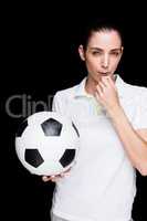 Female athlete blowing a whistle and holding a soccer ball