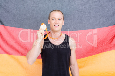 Athlete showing his gold medal in front of german flag