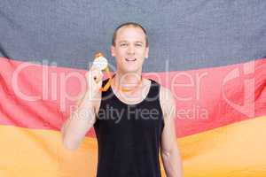 Athlete showing his gold medal in front of german flag