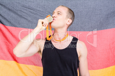 Athlete posing with gold medal in front of german flag