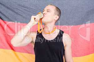 Athlete posing with gold medal in front of german flag