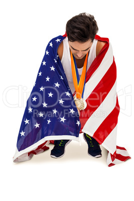 Athlete with gold medals around his neck wrapped in american fla