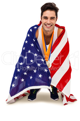 Athlete with gold medals around his neck wrapped in american fla