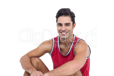 Portrait of happy athlete sitting on white background