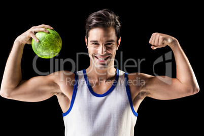 Portrait of happy athlete man holding ball and showing muscles