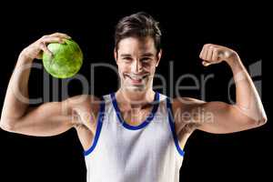 Portrait of happy athlete man holding ball and showing muscles