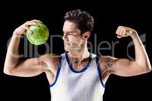 Confident athletic man holding ball and showing muscles