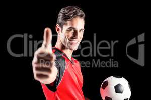 Portrait of male athlete holding football and showing thumbs up