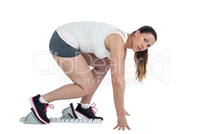 Confident athlete woman running from starting blocks