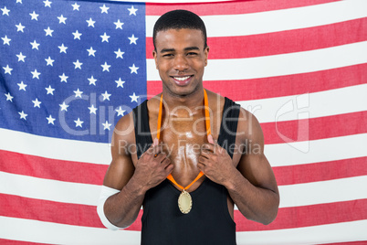 Athlete showing his gold medal in front of american flag