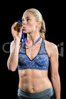 Happy female athlete kissing medal