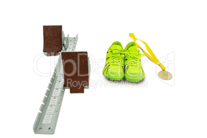 Trainer shoes, starting block and gold medal on white background