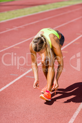 Female athlete tying her shoe laces on running track