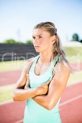 Female athlete standing with arms crossed on the running track