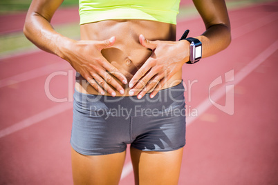 Mid-section of female athlete touching her belly