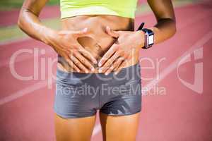 Mid-section of female athlete touching her belly