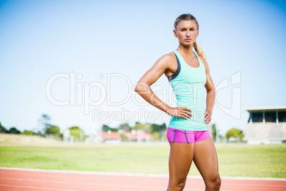 Confident female athlete standing with hand on hip Confident female athlete standing with hand on hip