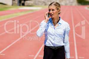Businesswoman talking on phone on a running track