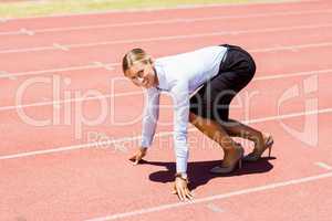 Portrait of businesswoman ready to run on running track