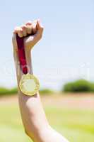 Hand of female athlete holding gold medal