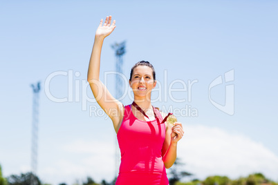 Female athlete waving her hand and showing gold medal