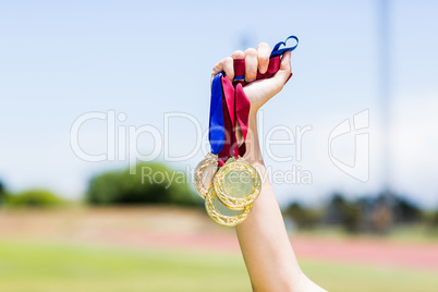 Hand of female athlete holding gold medals