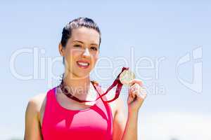 Portrait of female athlete showing her gold medal