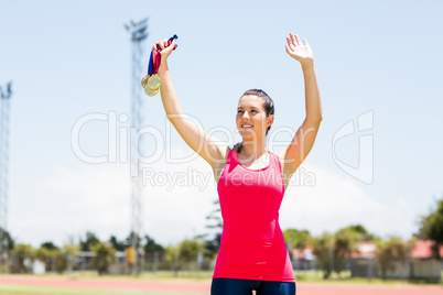 Female athlete waving her hand and showing gold medal