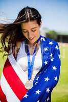 Female athlete wrapped in american flag with gold medal around h