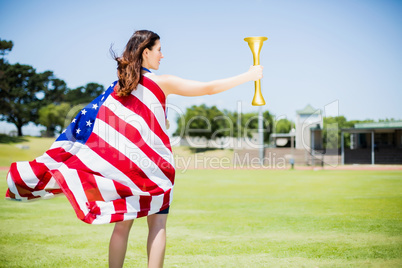 Female athlete wrapped in american flag holding fire torch