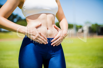 Mid-section of female athlete touching her belly