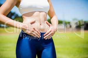 Mid-section of female athlete touching her belly