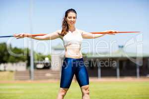 Happy female athlete carrying javelin on her shoulder