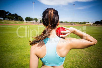 Rear view of female athlete preparing to throw shot put ball