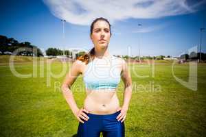 Confident female athlete standing with hand on hip